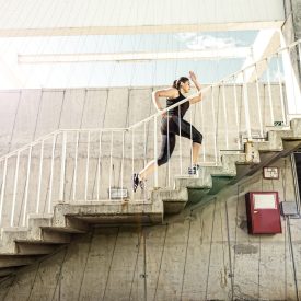 Running woman in black sports outfit, running up the stairs
